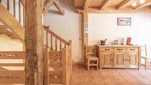 A wooden staircase leading to a kitchen area with a wooden cabinet and a chair. - Chalet 'Les Laouchets -  8 Pers' with Mountain View, Balcony and Wi-Fi (Sixt-Fer-à-Cheval)