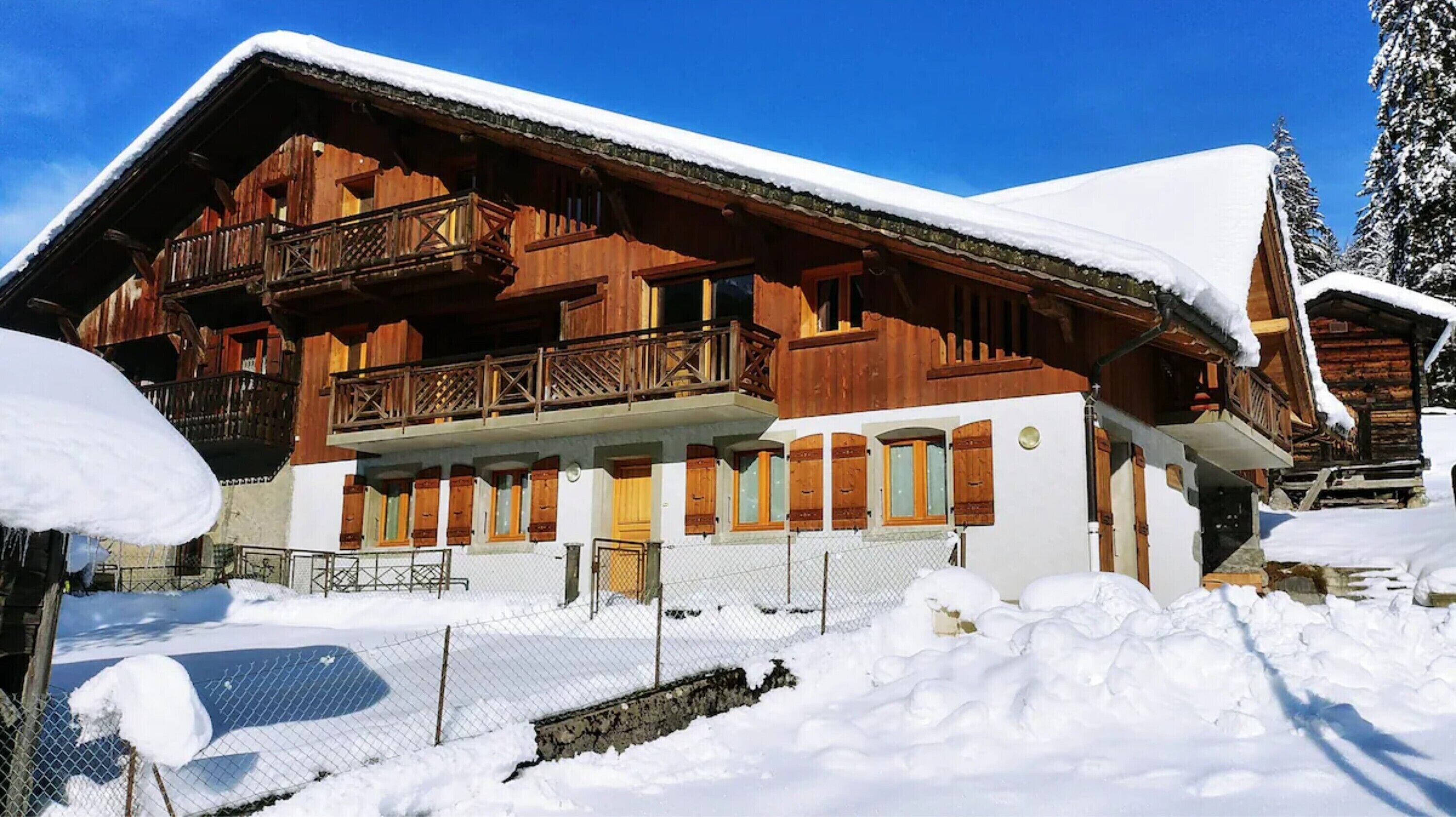 Un chalet en bois doté d’un balcon, entouré de neige.