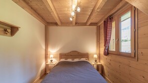 A bedroom with a wooden ceiling, a bed with a headboard, two bedside lamps, and a window with curtains. - Chalet 'Les Salamanes -  6-7 Pers' with Mountain View, Balcony and Wi-Fi (Sixt-Fer-à-Cheval)