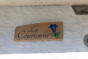 Un letrero de madera con el texto 'La Courtonne' y una ilustración de una flor azul.