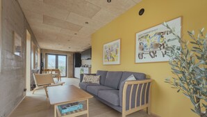 A living room with a sofa, a coffee table, and a plant. There are framed pictures on the wall. - A Varoa Apartments (Torshavn)