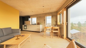 A modern interior with a sofa, dining table, chairs, and a kitchen area. - A Varoa Apartments (Torshavn)