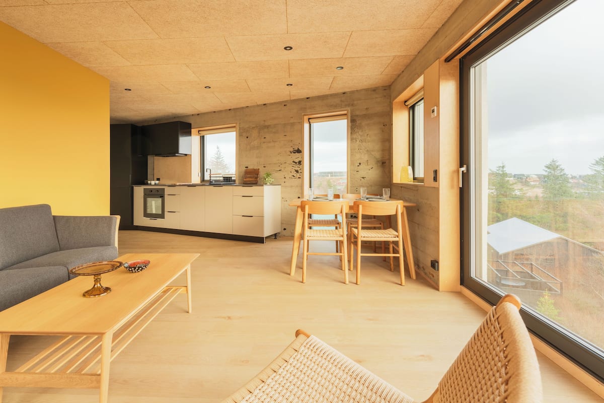 Ein modernes Interieur mit einer Couch, einem Esstisch, Stühlen und einer Küchenzeile.
