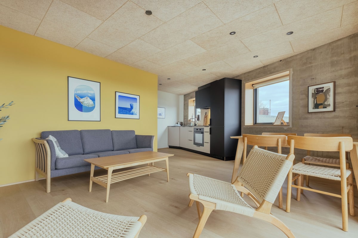 Ein modernes Wohnzimmer mit einer Couch, einem Couchtisch und Korbstühlen.