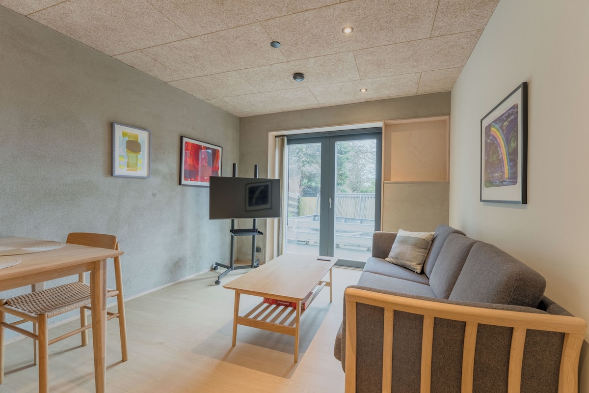 Ein modernes Wohnzimmer mit einer Couch, einem Couchtisch, einem Fernseher und Kunstwerken an den Wänden.