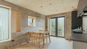 A modern kitchen with a large island, wooden chairs, and a view of greenery outside. - A Varoa Apartments (Torshavn)