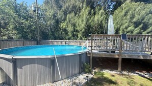 Une piscine hors sol dotée d’une terrasse en bois et d’un escalier en métal.