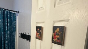 Une porte blanche ornée de deux petites plaques décoratives, un rideau bleu et un porte-manteau noir.