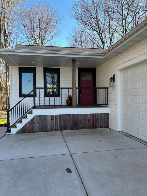 A residential house with a covered porch, a red door, and a garage.