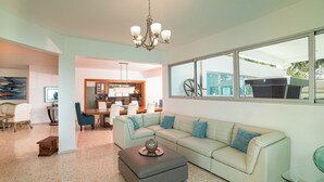 A modern living room with a sectional sofa, a glass coffee table, and a chandelier.