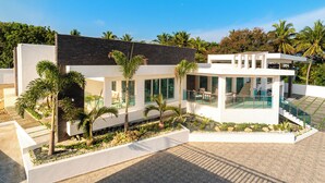 A modern house with a pool, surrounded by palm trees and a well-maintained garden.