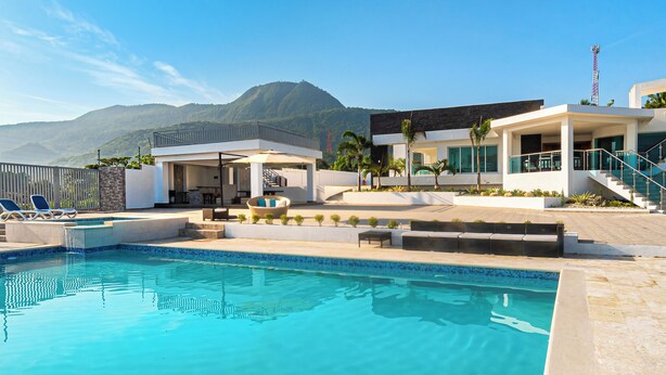 A modern resort with a swimming pool, outdoor seating, and a view of mountains.