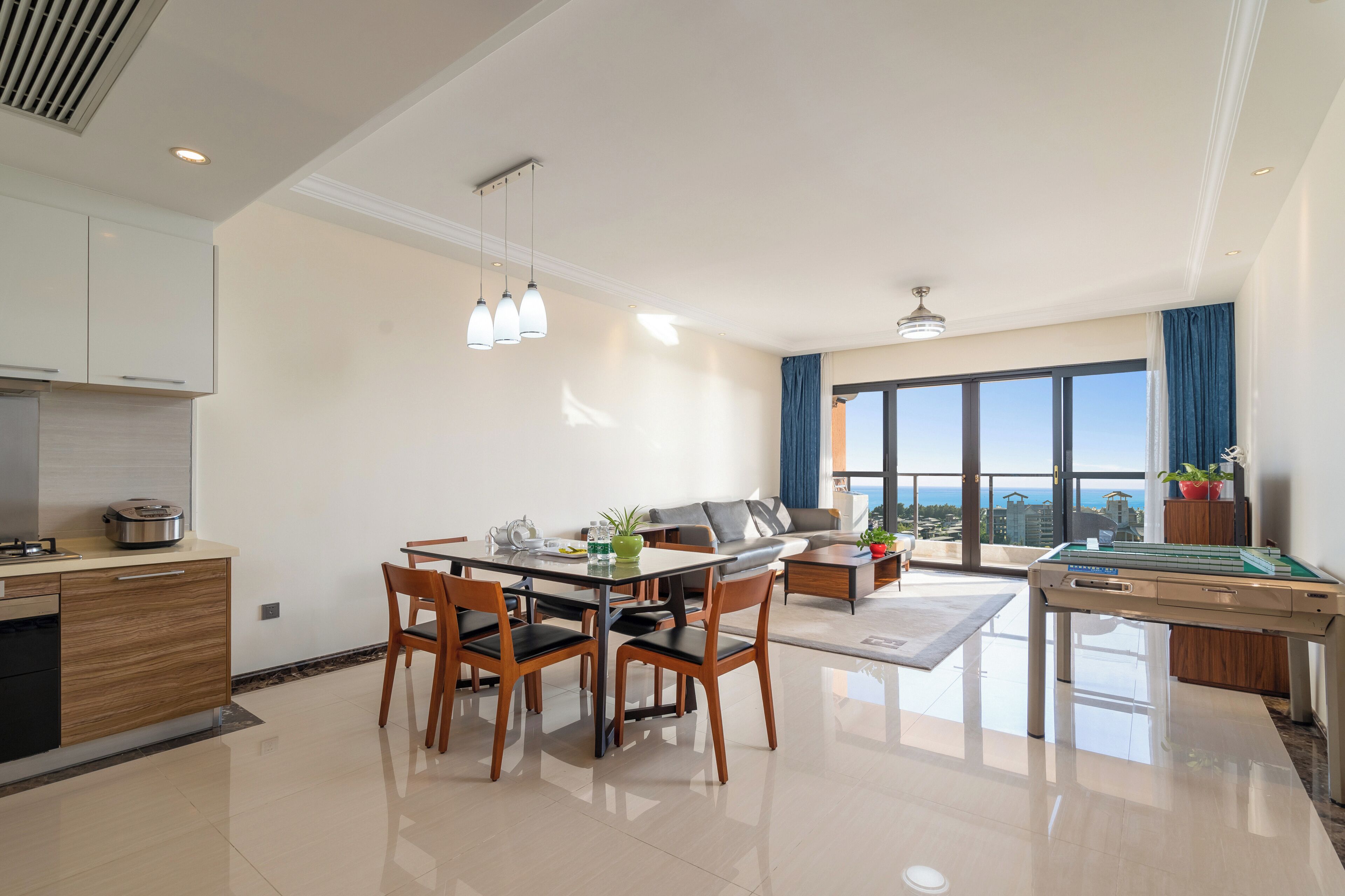 A modern living room with a dining area, a pool table, and a large window offering a city view.
