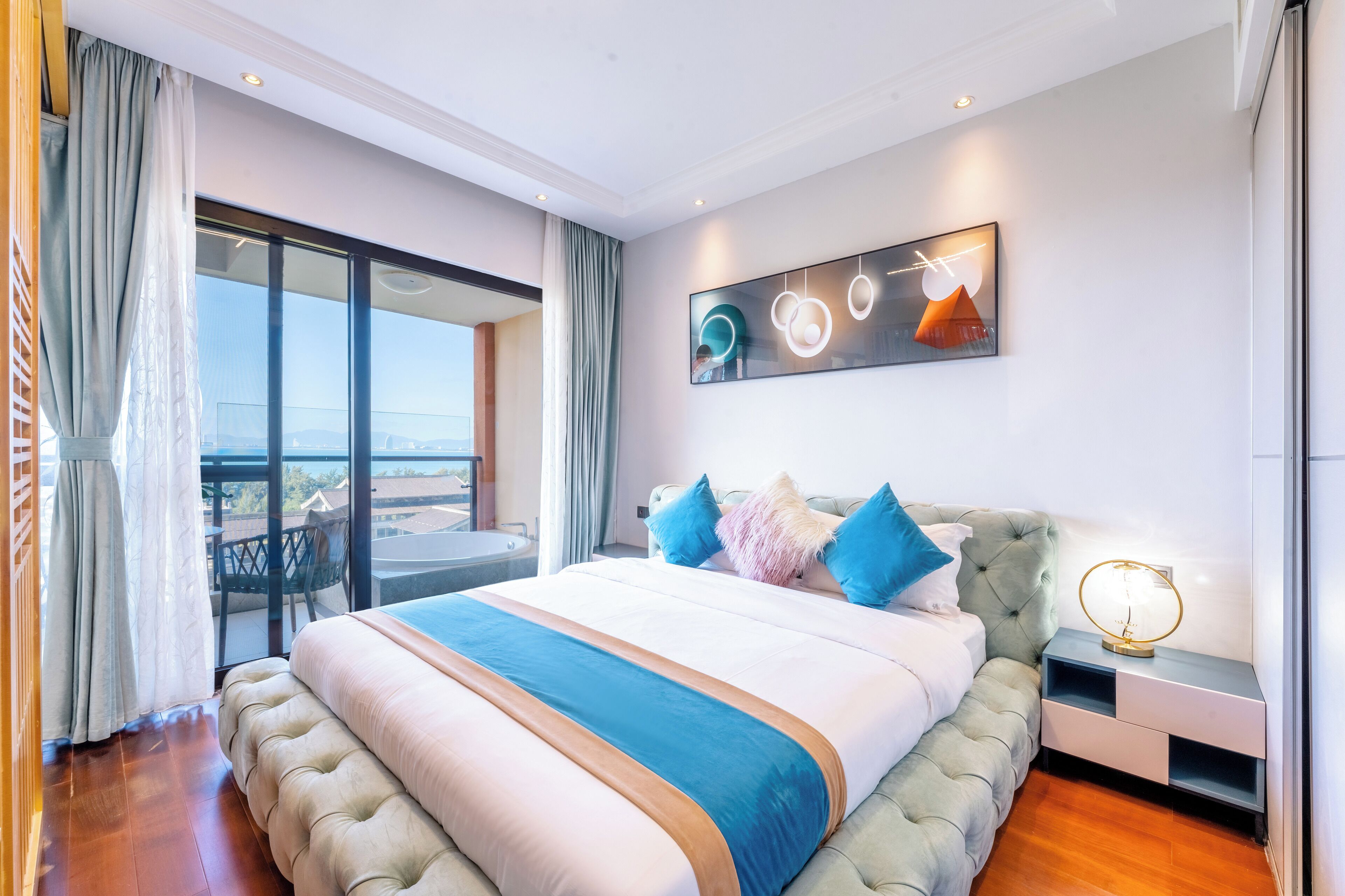 A spacious bedroom with a large bed, a balcony with a view, and a modern art piece on the wall.