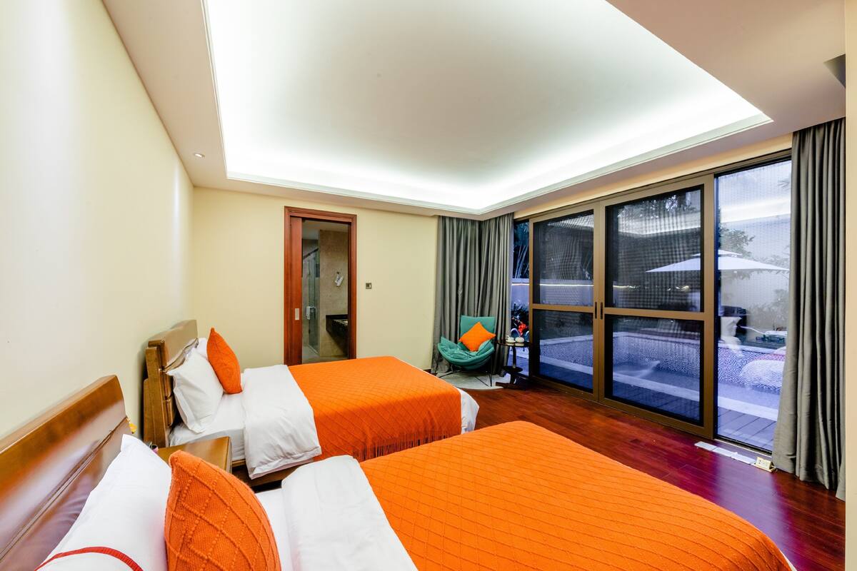 A hotel room with two beds, a large window, a chair, and a view of the outside.