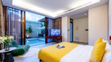 Ein Hotelzimmer mit einem großen Bett, einem Fernseher, einem kleinen Pool und einem Balkon mit Vorhängen.