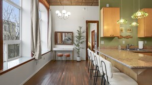Una cocina moderna con techo de madera, encimera blanca y una zona de bar con taburetes.