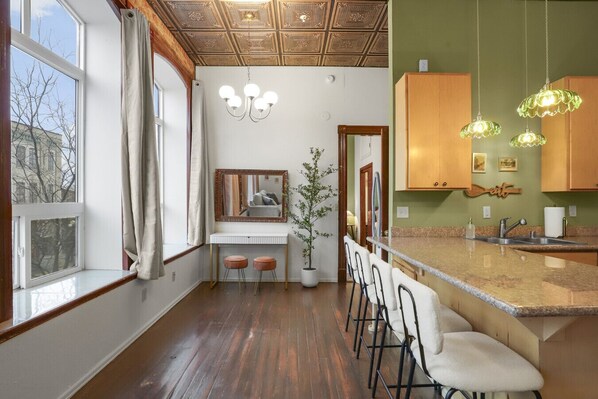 Una cocina moderna con techo de madera, encimera blanca y una zona de bar con taburetes.