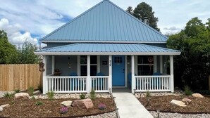 A two-story house with a blue roof, white exterior, and a front porch with railings. - Baybeary Cottage, Bayfield base camp for Fun, Family & Adventure near Durango (Bayfield)