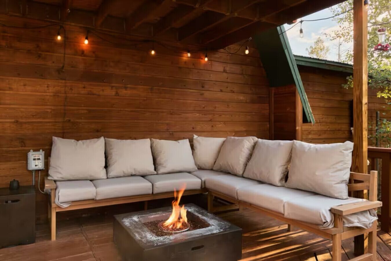 Un patio in legno con un focolare integrato e un divano angolare beige.