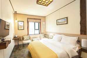 A hotel room with a bed, bedside table, lamp, chair, and a window with curtains. - Daocheng Yading Shiruo Hotel (Garze)
