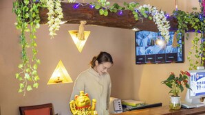 A reception desk with a decorative golden cat figurine, a computer monitor, and a plant in a glass vase. - Daocheng Yading Shiruo Hotel (Garze)