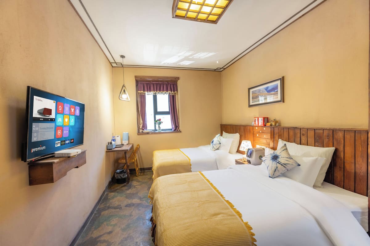 Een hotelkamer met twee bedden, een televisie, een bureau en een raam met gordijnen.
