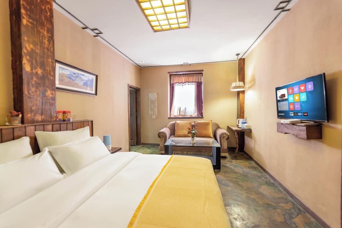 Een hotelkamer met een bed, een bank, een televisie en een bureau met een lamp.