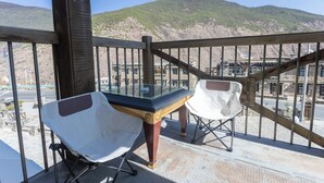 A balcony with a glass table and two white chairs, overlooking a mountainous landscape. - Daocheng Yading Shiruo Hotel (Garze)