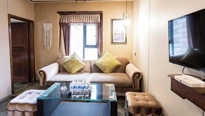 A living room with a sofa, ottoman, and a glass coffee table with water bottles. - Daocheng Yading Shiruo Hotel (Garze)