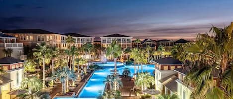 A resort with multiple swimming pools, palm trees, and hotel buildings.