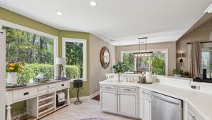 Una cocina amplia con armarios blancos, una isla grande y vistas al exterior.