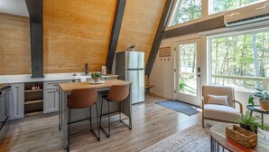 A modern kitchen with a wooden ceiling, a large window, and a refrigerator. - Jackson A Frame (Rossville)