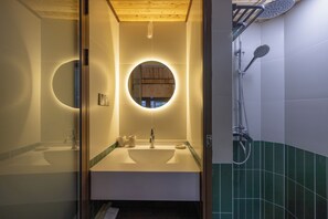 A modern bathroom with a central sink, a round mirror, and a shower with a handheld showerhead.