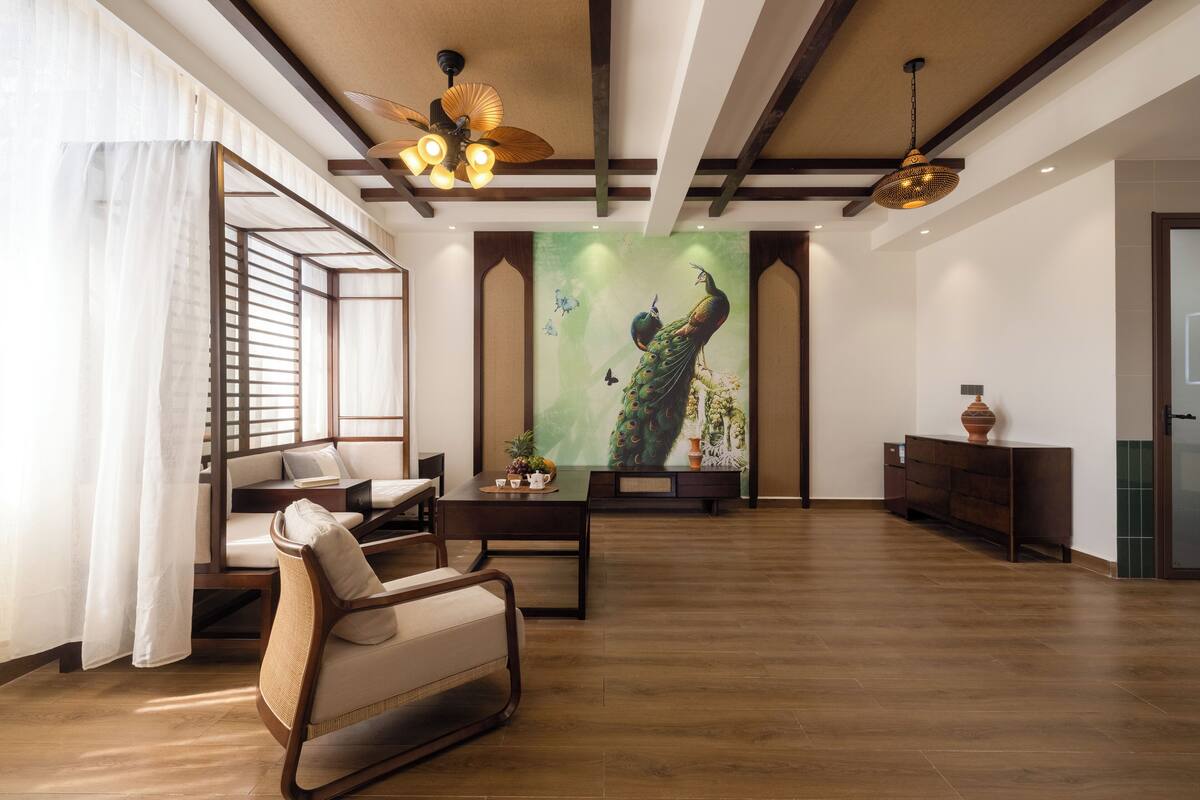 A spacious living room with a wooden floor, a sofa, a coffee table, and a painting of a peacock.