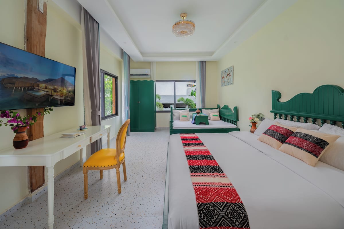 A hotel room with a bed, a desk, a chair, a TV, and a view of the outdoors.
