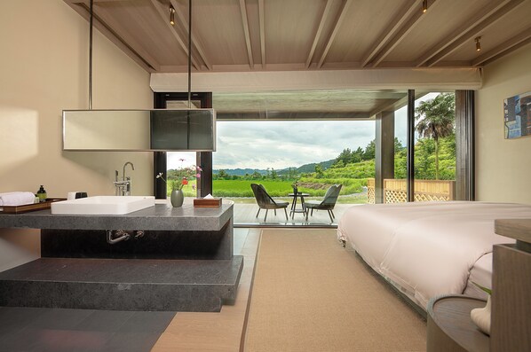 Un baño moderno con un lavamanos amplio, un espejo y vistas a un paisaje exuberante.