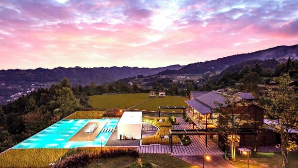 A large swimming pool with a deck, a wooden cabin, and a view of a valley. - Country Retreats Zhangjiajie Manson Resort (Zhangjiajie)