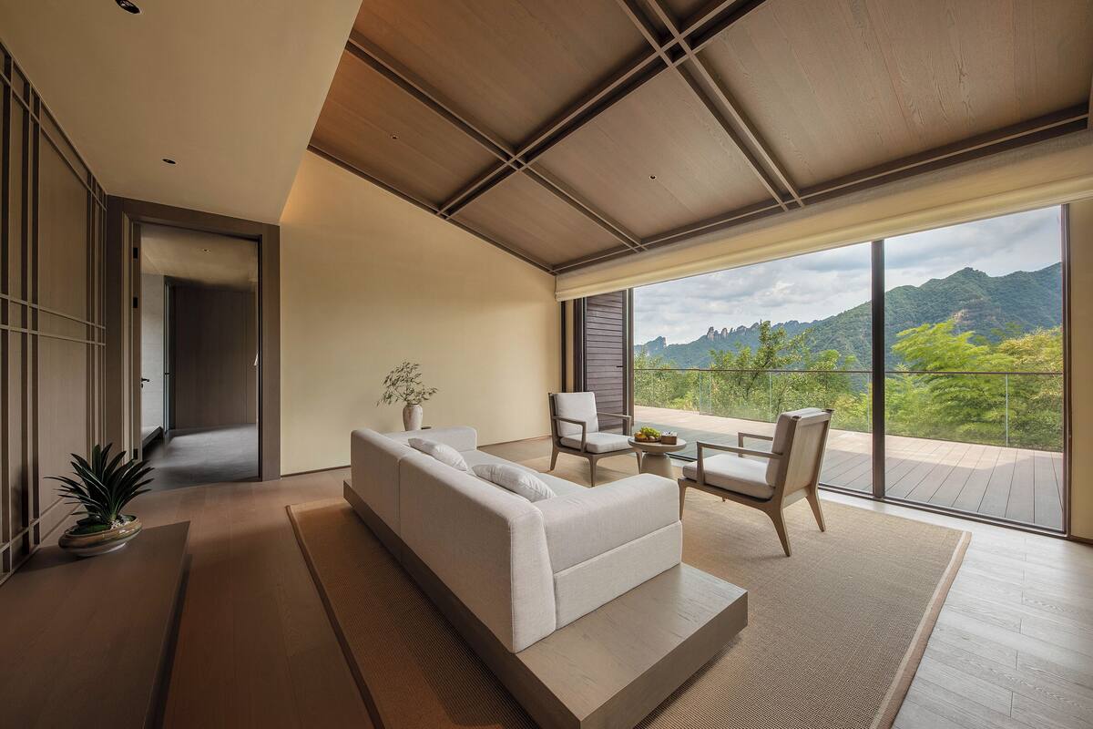Un salon moderne avec un canapé, des fauteuils et une grande fenêtre donnant sur les montagnes.