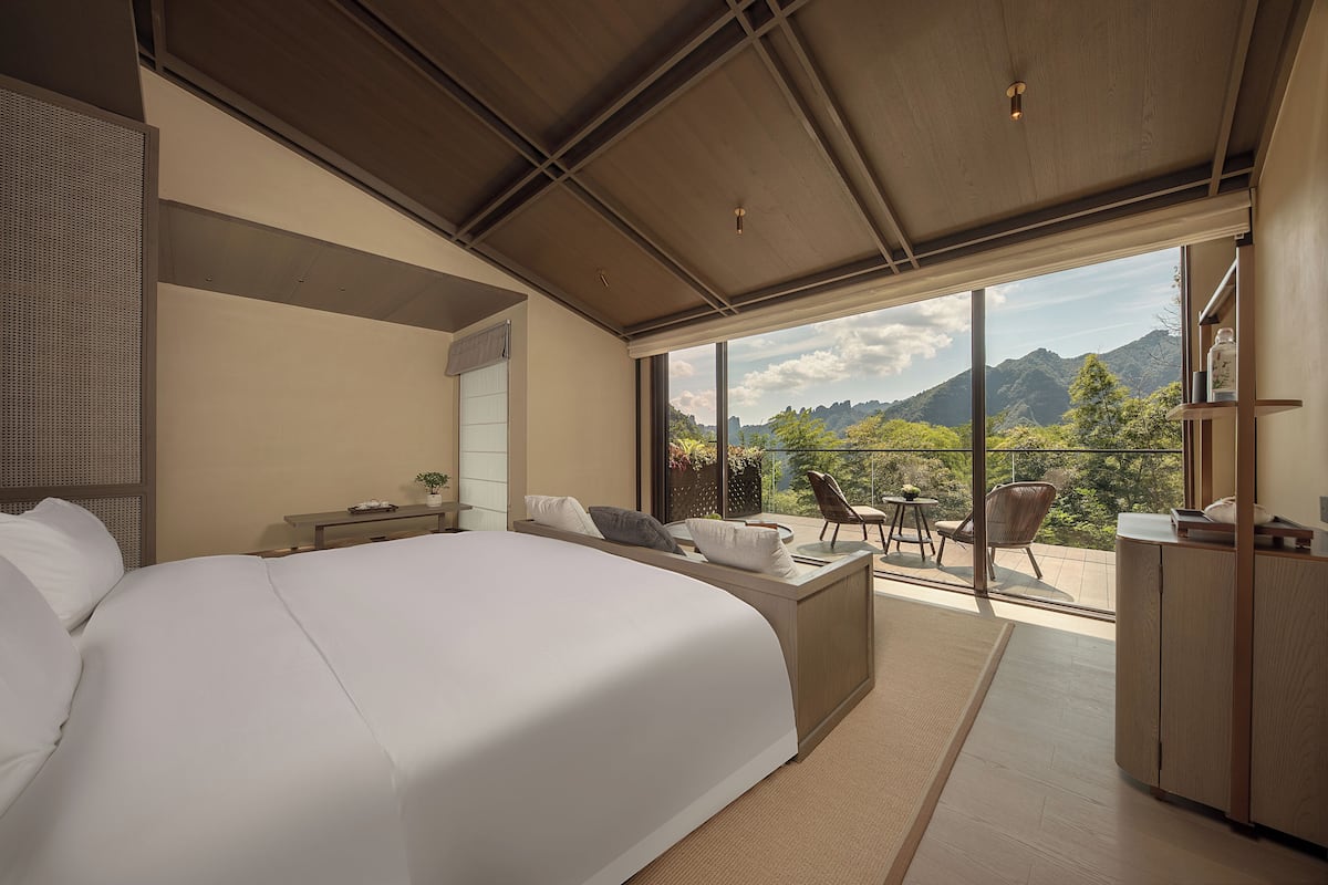 Une chambre moderne dotée d’un grand lit, d’un bureau et d’un balcon offrant une vue sur les montagnes.