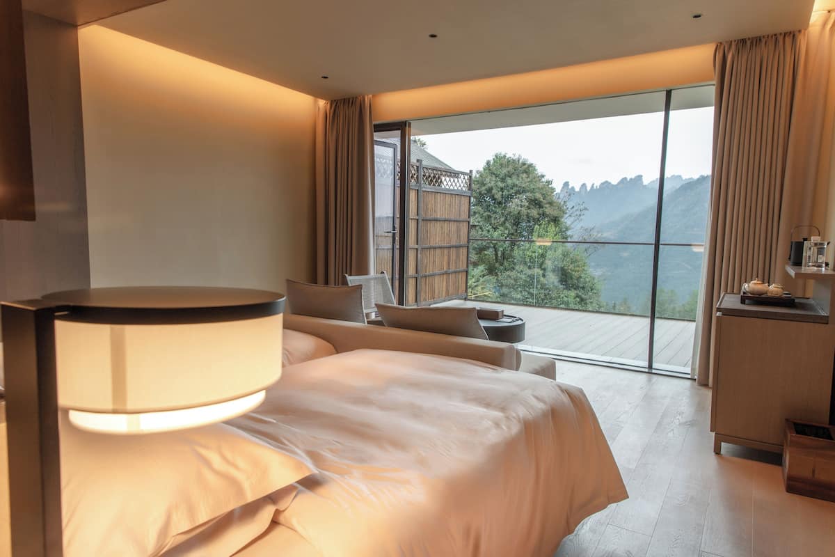 Une chambre d’hôtel moderne, dotée d’un grand lit, d’un bureau et offrant une vue sur l’extérieur.