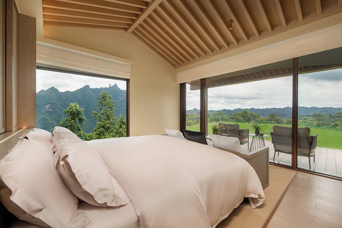 Une chambre avec un grand lit, un bureau et une vue sur les montagnes.