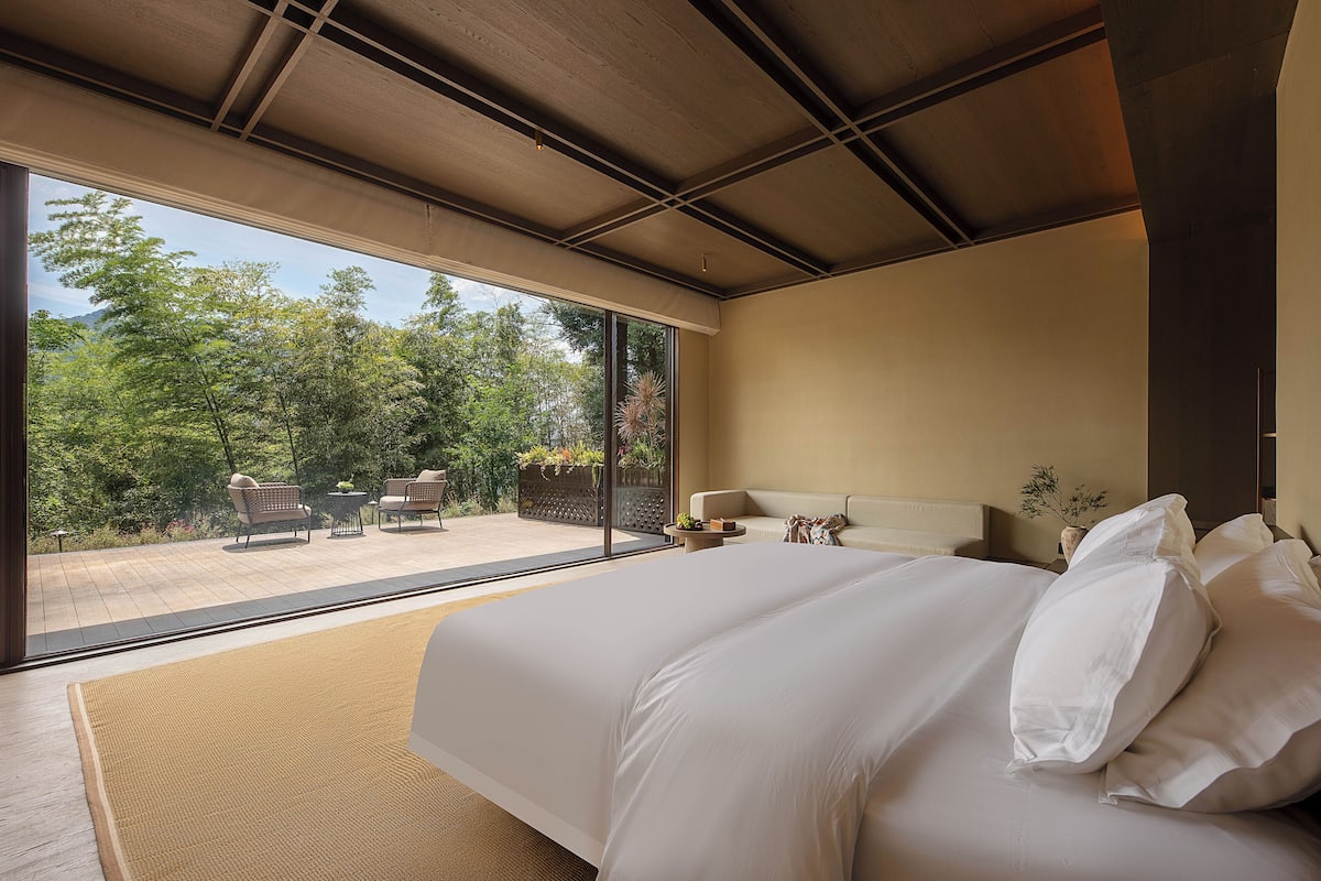 Une chambre dotée d’un grand lit, d’un canapé et donnant sur un patio aménagé avec du mobilier d’extérieur.