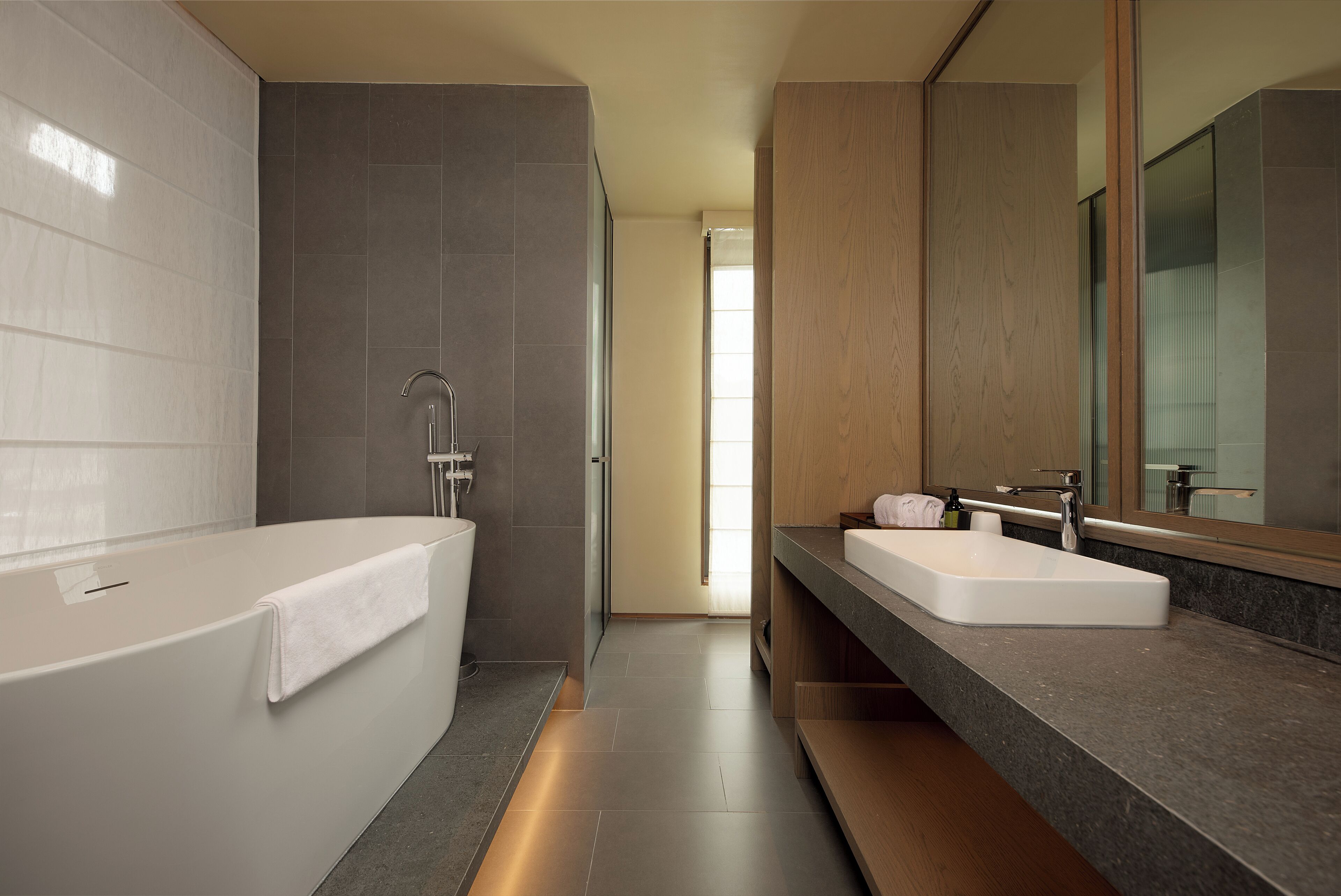 A modern bathroom with a bathtub, a sink, and a large mirror.