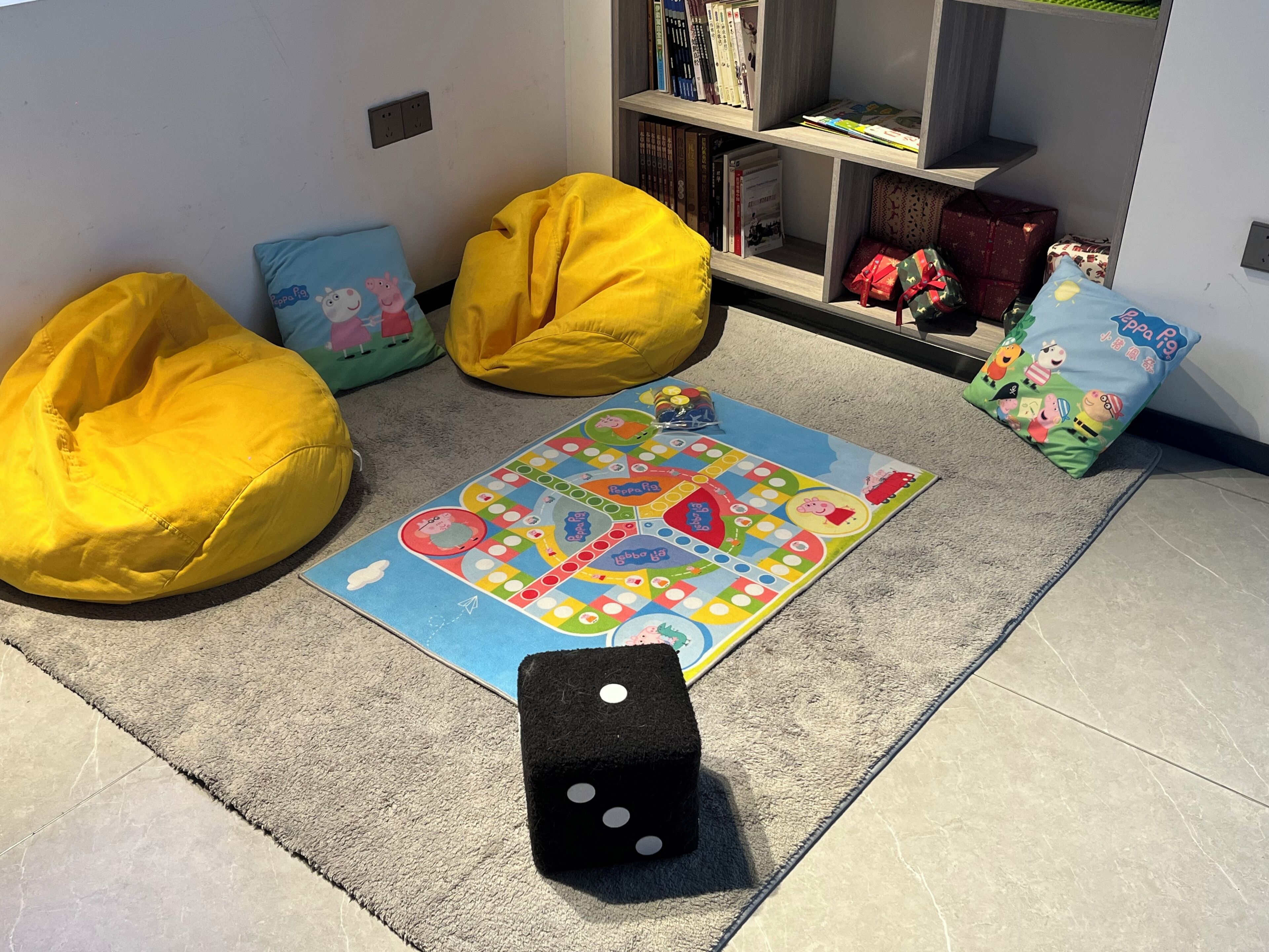 Zona de juegos con sillones de pufs, juegos de mesa y una estantería.