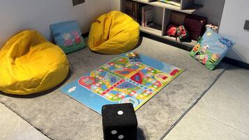 Zona de juegos con sillones de pufs, juegos de mesa y una estantería.