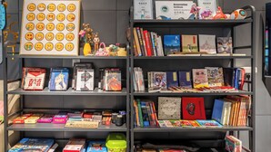 Una estantería con varios libros, un certificado y una colección de tarjetas con emojis.