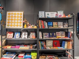 Una estantería con varios libros, un certificado y una colección de tarjetas con emojis.