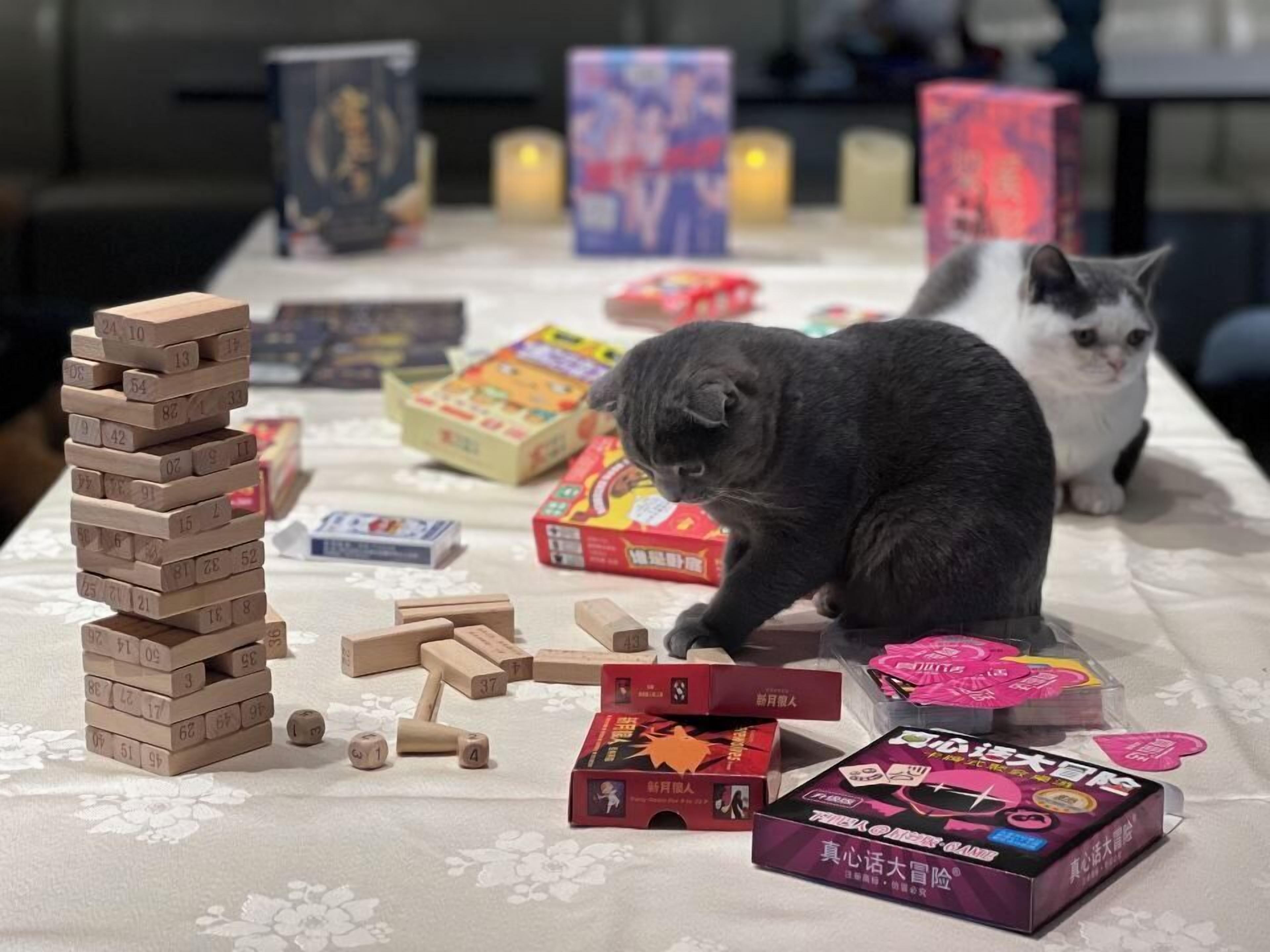 Une table sur laquelle se trouve une tour de Jenga, des pièces de jeu éparpillées et diverses boîtes, dont une boîte rose en forme de cœur.