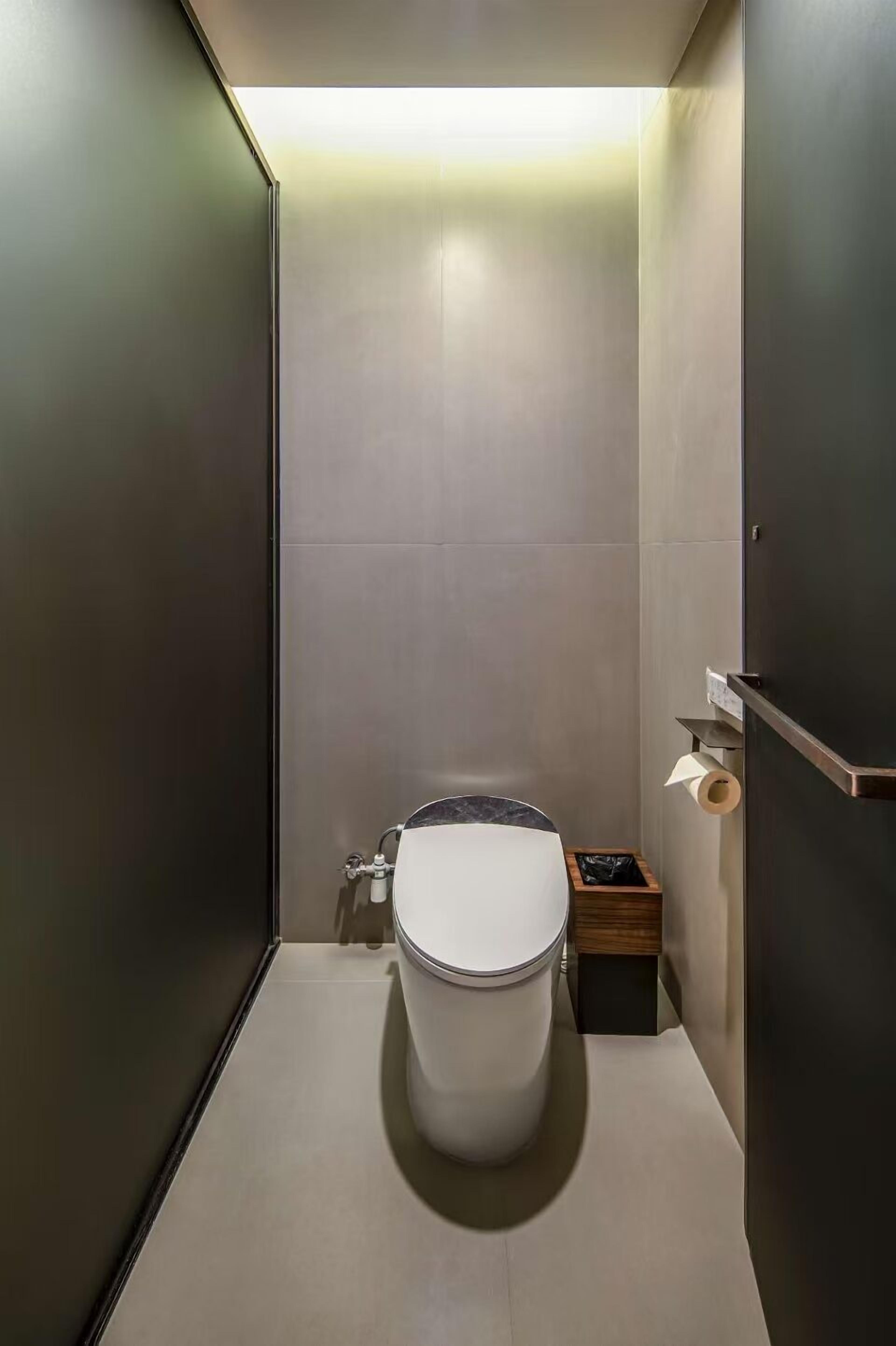 Un bagno moderno e funzionale con il water, un cestino e un porta carta igienica a parete.